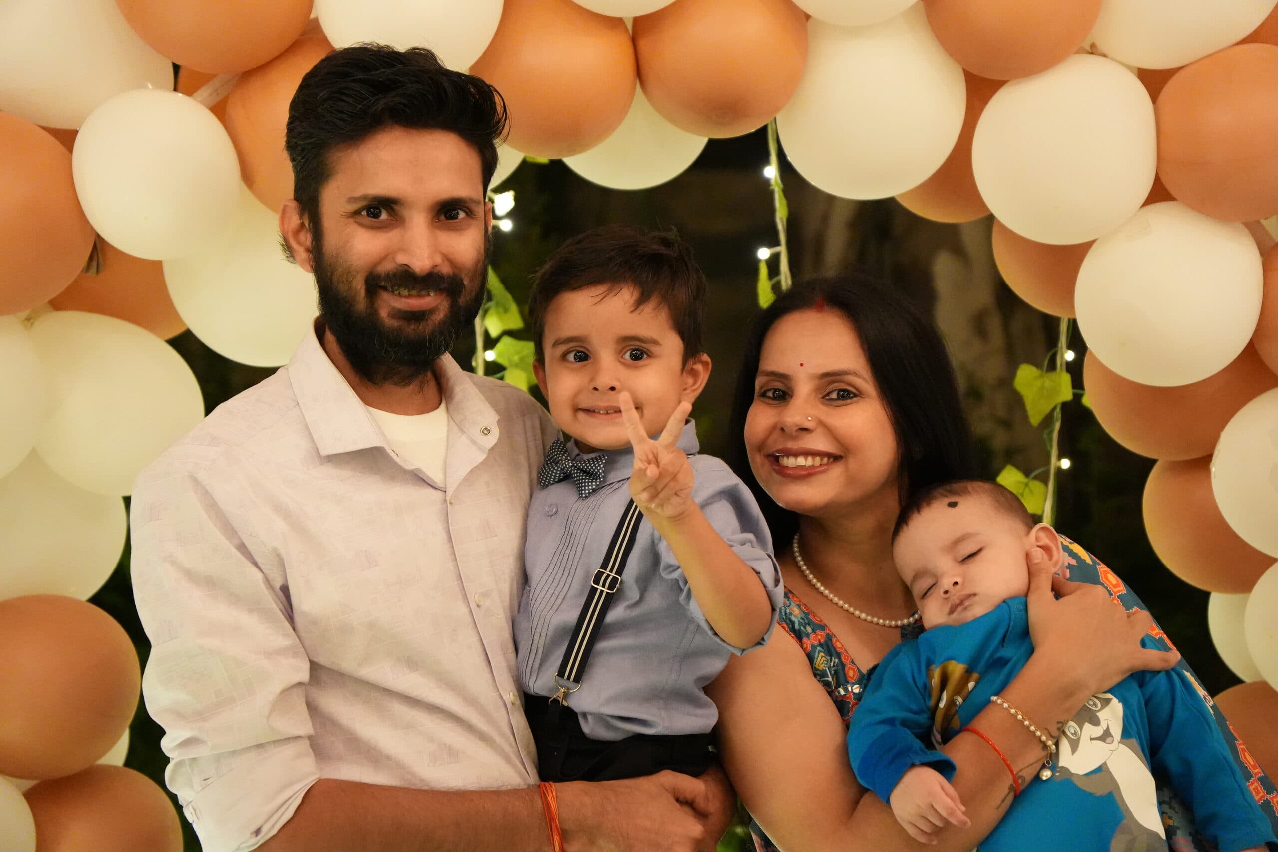 A family of four beneath a balloon arch